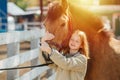 Happy ginger girl holding horse`s snout, touching horse`s head with hers