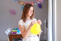 Happy preteen girl blowing yellow balloon decorating house preparing to kids birthday party