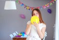Happy preteen girl blowing yellow balloon decorating house preparing to kids birthday party with set up table Royalty Free Stock Photo