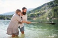 Happy preteen girl and father with fishing net on summer holiday by lake.