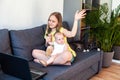 Happy preteen girl with her infant sister looking at laptop screen and gesturing hello while having video call. Royalty Free Stock Photo