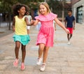 Happy preteen girls running skipping gaily along city street Royalty Free Stock Photo