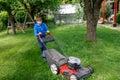 Happy preteen kid boy with lawn mower. Portrait of smiling teenager child working in garden, trimming grass. Garden Royalty Free Stock Photo