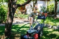 Happy preteen kid boy with lawn mower. Portrait of smiling teenager child working in garden, trimming grass. Garden Royalty Free Stock Photo