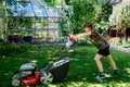 Happy preteen kid boy with lawn mower. Portrait of smiling teenager child working in garden, trimming grass. Garden Royalty Free Stock Photo