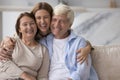 Happy pretty adult woman hugging positive older parents with love Royalty Free Stock Photo