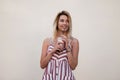 Happy pretty beautiful young blond woman in a stylish summer pink striped dress with a sweet cold milk drink rest