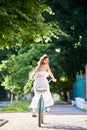 Happy pretty brunette looks back wile riding blue bike down green park alley. Royalty Free Stock Photo
