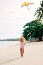 Happy pretty child girl with a kite running on tropical beach in summer Royalty Free Stock Photo