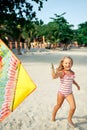 Happy pretty child girl with a kite running on tropical beach in summer Royalty Free Stock Photo
