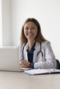 Happy pretty doctor woman sitting at work table in hospital Royalty Free Stock Photo