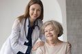 Happy pretty female doctor with stethoscope embracing older patient Royalty Free Stock Photo
