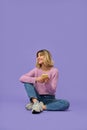 Happy pretty gen z blonde girl using cell phone isolated on purple background.