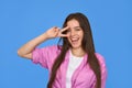 Happy gen z Latin girl showing peace sign over face isolated on blue. Portrait Royalty Free Stock Photo