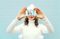 Happy pretty girl taking photo self portrait on smartphone over blue background in a winter knitted clothes Royalty Free Stock Photo