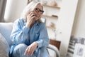 Happy mature woman speaking on smartphone. Senior grey haired lady making telephone call, sitting on couch at home Royalty Free Stock Photo