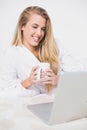Happy pretty model looking at her laptop lying on cosy bed Royalty Free Stock Photo