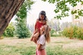 Happy pretty mother playing and riding on her shoulder her daughter in the park. Happy kid having fun with her mom enjoying the Royalty Free Stock Photo