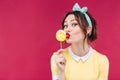 Happy pretty pinup girl eating and kissing yellow lollipop Royalty Free Stock Photo