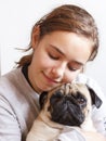 Happy pretty smiling teenager girl hugging pug dog with love Royalty Free Stock Photo