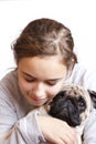 Happy pretty smiling teenager girl hugging pug dog with love Royalty Free Stock Photo