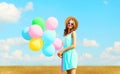 Happy pretty smiling young woman holds an air colorful balloons enjoying a summer day on a meadow blue sky Royalty Free Stock Photo