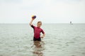 Happy teen girl in neoprene swimingsuit  playing with ball and running in sea Royalty Free Stock Photo