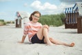 Happy pretty teen girl sitting on sunny white beach at summer holidays Royalty Free Stock Photo