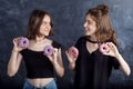 Happy pretty teenage girls with donuts having fun. Portrait of joyful girls with donuts on black background. Good mood, diet Royalty Free Stock Photo