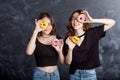 Happy pretty teenage girls with donuts having fun. Portrait of joyful girls with donuts on black background. Good mood, diet Royalty Free Stock Photo