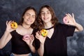 Happy pretty teenage girls with donuts having fun. Portrait of joyful girls with donuts on black background. Good mood, diet Royalty Free Stock Photo