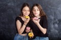 Happy pretty teenage girls with donuts having fun. Portrait of joyful girls with donuts on black background. Good mood, diet Royalty Free Stock Photo