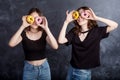 Happy pretty teenage girls with donuts having fun. Portrait of joyful girls with donuts on black background. Good mood, diet Royalty Free Stock Photo