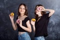 Happy pretty teenage girls with donuts having fun. Portrait of joyful girls with donuts on black background. Good mood, diet Royalty Free Stock Photo