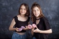 Happy pretty teenage girls with donuts having fun. Portrait of joyful girls with donuts on black background. Good mood, diet Royalty Free Stock Photo