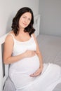 happy pretty woman enjoying pregnancy. mother to be is expecting parent. cute big tummy. pregnant brunette in light room