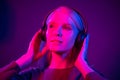 Happy pretty woman with headphones listening to music over red neon background at studio Royalty Free Stock Photo