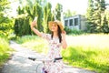 Happy pretty young girl bicycling and selfie on summer park. Happy relax time in city. Beautiful woman, sunny day