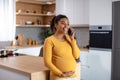 Happy pretty young pregnant african american woman touching belly and talking by phone Royalty Free Stock Photo