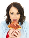 Happy Pretty Young Woman Eating a Fresh Slice of Pepperoni and Ham Pizza Royalty Free Stock Photo