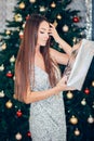 Happy pretty young woman holding gift box near christmas tree Royalty Free Stock Photo