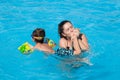 Happy pretty young woman mother kissing her swimming little child foot with love in blue fresh water summer outdoor pool Royalty Free Stock Photo