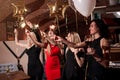 Happy pretty young women holding firework sparklers, balloons, glasses of wine celebrating a holiday in restaurant with Royalty Free Stock Photo