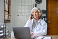 Happy and professional Asian aged female doctor talking on the phone with someone Royalty Free Stock Photo