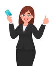 Happy, professional business woman showing/holding credit/debit/ATM banking card and gesturing/making thumbs up sign. Good, like. Royalty Free Stock Photo