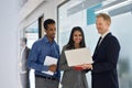 Happy professional diverse team people standing in office looking at laptop. Royalty Free Stock Photo