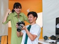 Happy professional male photographer holding DSLR camera smiling while showing pictures on camera screen to pretty young model who Royalty Free Stock Photo