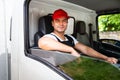 Happy professional truck driver with his assistant wearing a red cap, smiling, looking at the camera from a truck window. Royalty Free Stock Photo