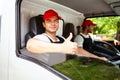 Happy professional truck driver with his assistant wearing a red cap thumb up, smiling, looking at the camera from a truck window Royalty Free Stock Photo