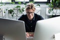 Happy programmer in eyeglasses using computers